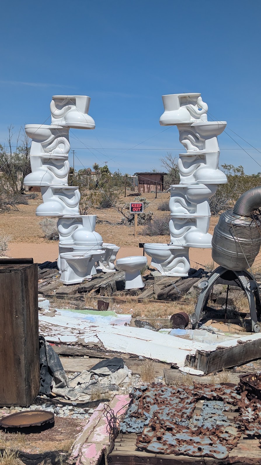 A large upside arch of white porcelain toilets, beautifully framing a keep out sign